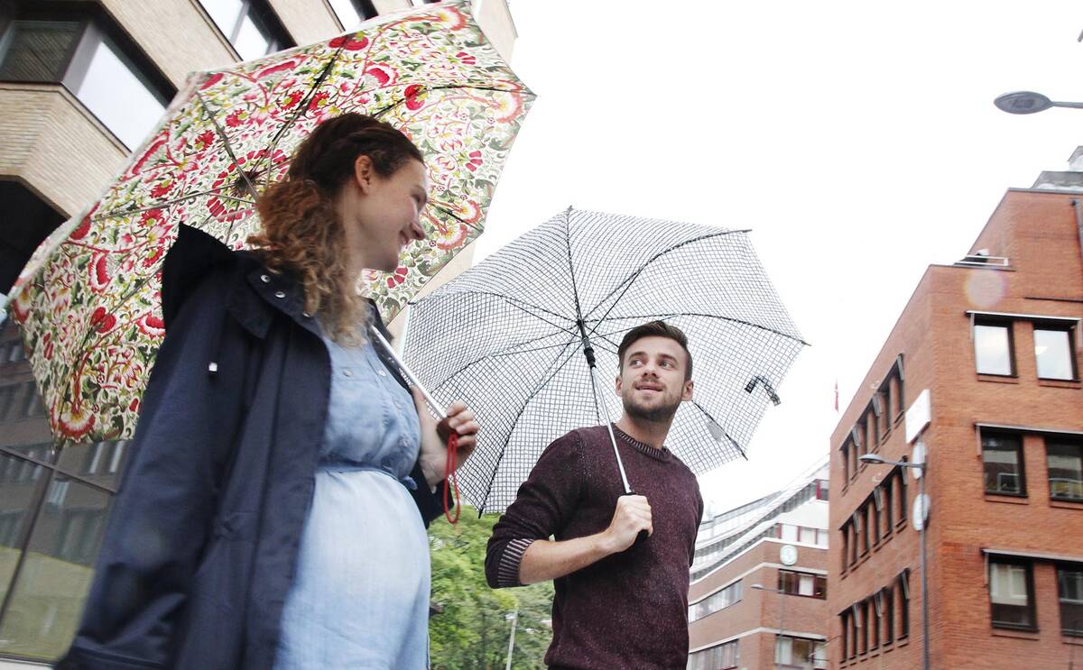 Två unga personer med paraplyer promenerar utomhus 