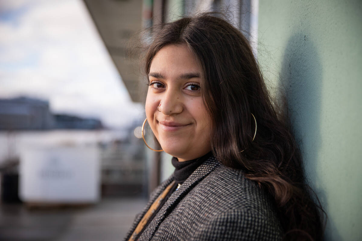 En kvinna med stora örhängen ler milt mot kameran