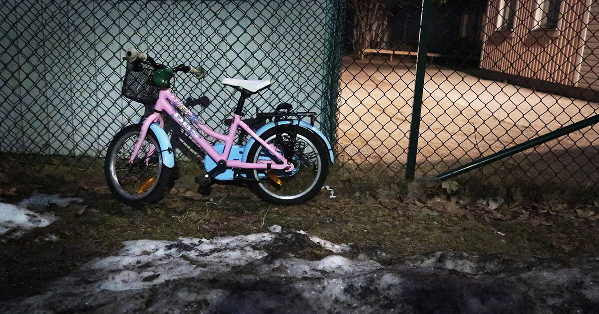 Övergiven barncykel vid ett staket