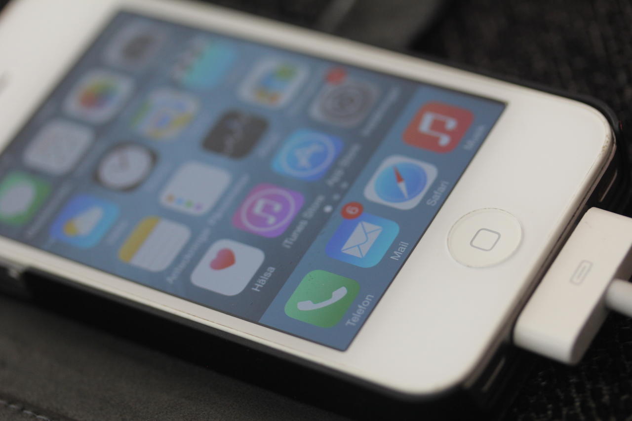 Bilden visar en iPhone på laddning, med app-ikonerna synliga.