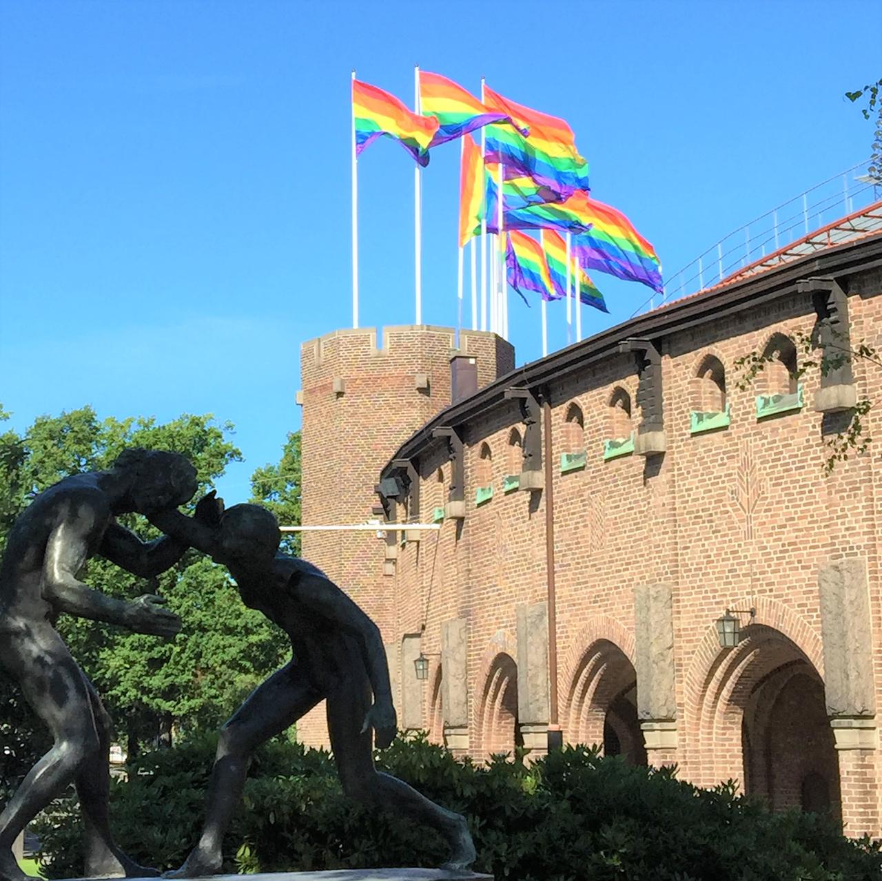 Bild från Stockholm Pride 2016. Regnbågsflaggor vajar i vinden över Stadion i Stockholm.