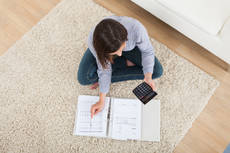 9803426-woman-calculating-home-finances-on-rug.jpg