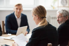 24823972-focused-serious-businesswoman-reading-document-at-group.jpg