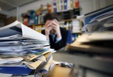 18286996-frustrated-man-sitting-desperate-over-paper-work-at-desk.jpg