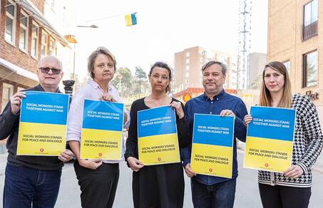 Fem personer med skyltar med texten Social Workers stand together against war